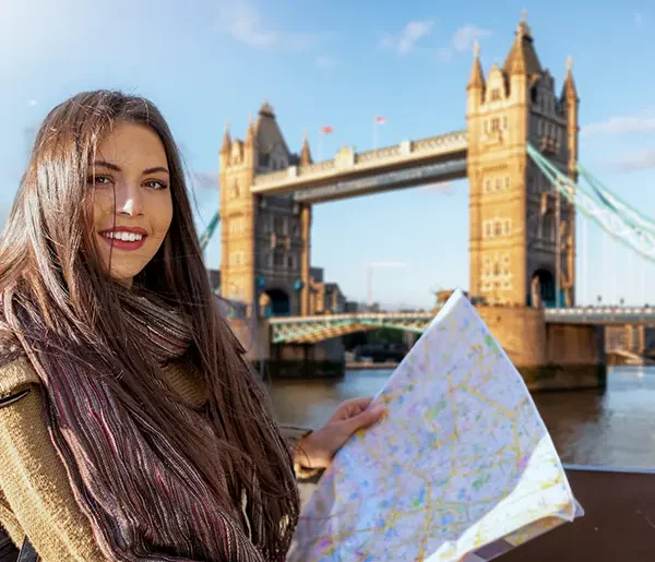 Junge Frau mit Karte vor der Tower Bridge über der Themse in London, Vereinigtes Königreich.