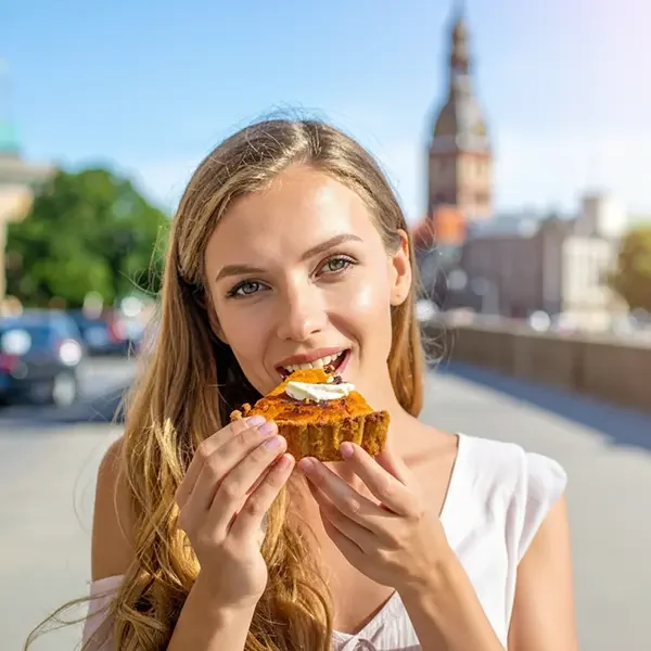 Frau isst ein Sklandrausis in Riga.
