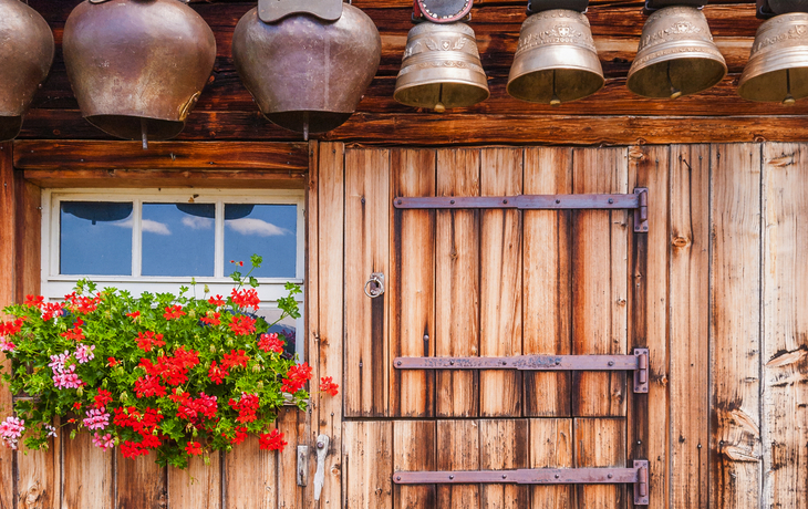 alte Kuhglocken unter dem Dach einer Almhütte in der Schweiz