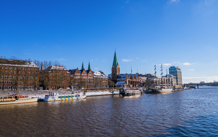 Blick von der Fußgängerbrücke auf die Weser mit einigen Booten im Sonnenlicht in Bremen im Winter