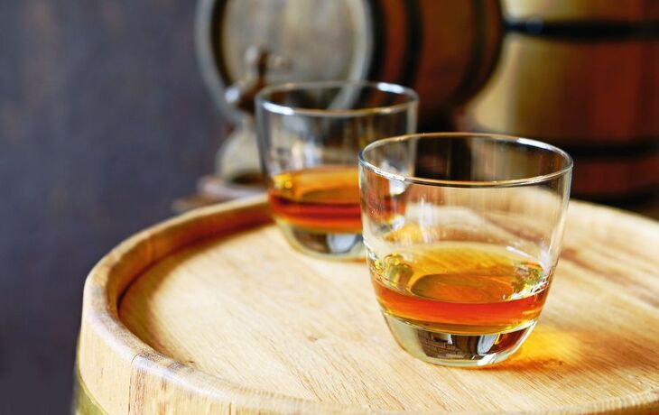 Glasses of brandy in cellar with old barrels