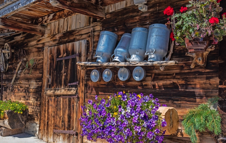 hölzerne Alm mit Milchkannen und Blumen