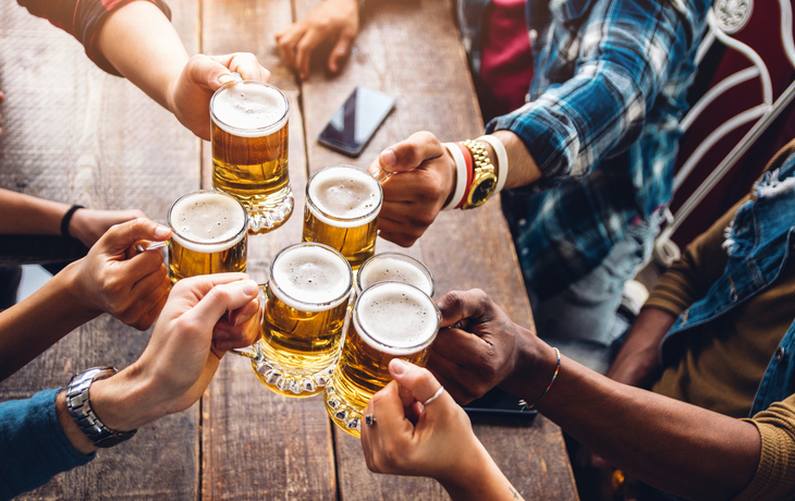 Eine Gruppe von Leuten genießt und stößt mit einem Bier in der Brauereigaststätte an.