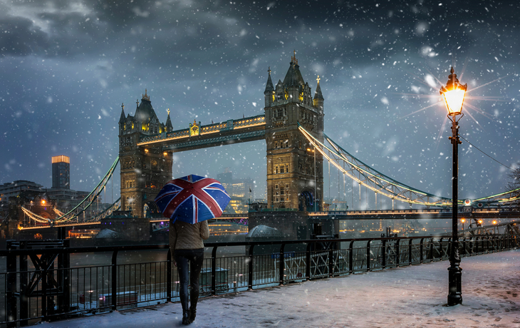 Londoner Winterkonzept - Tourist mit Schirm mit britischer Flagge vor der Tower Bridge