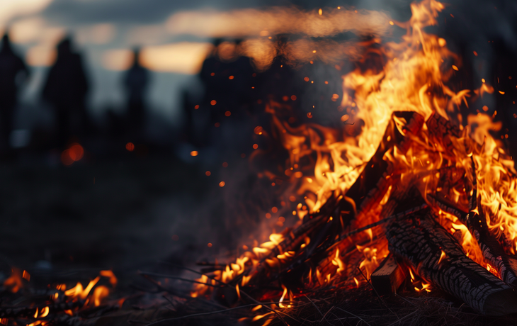 Lagerfeuer mit Menschen im Hintergrund